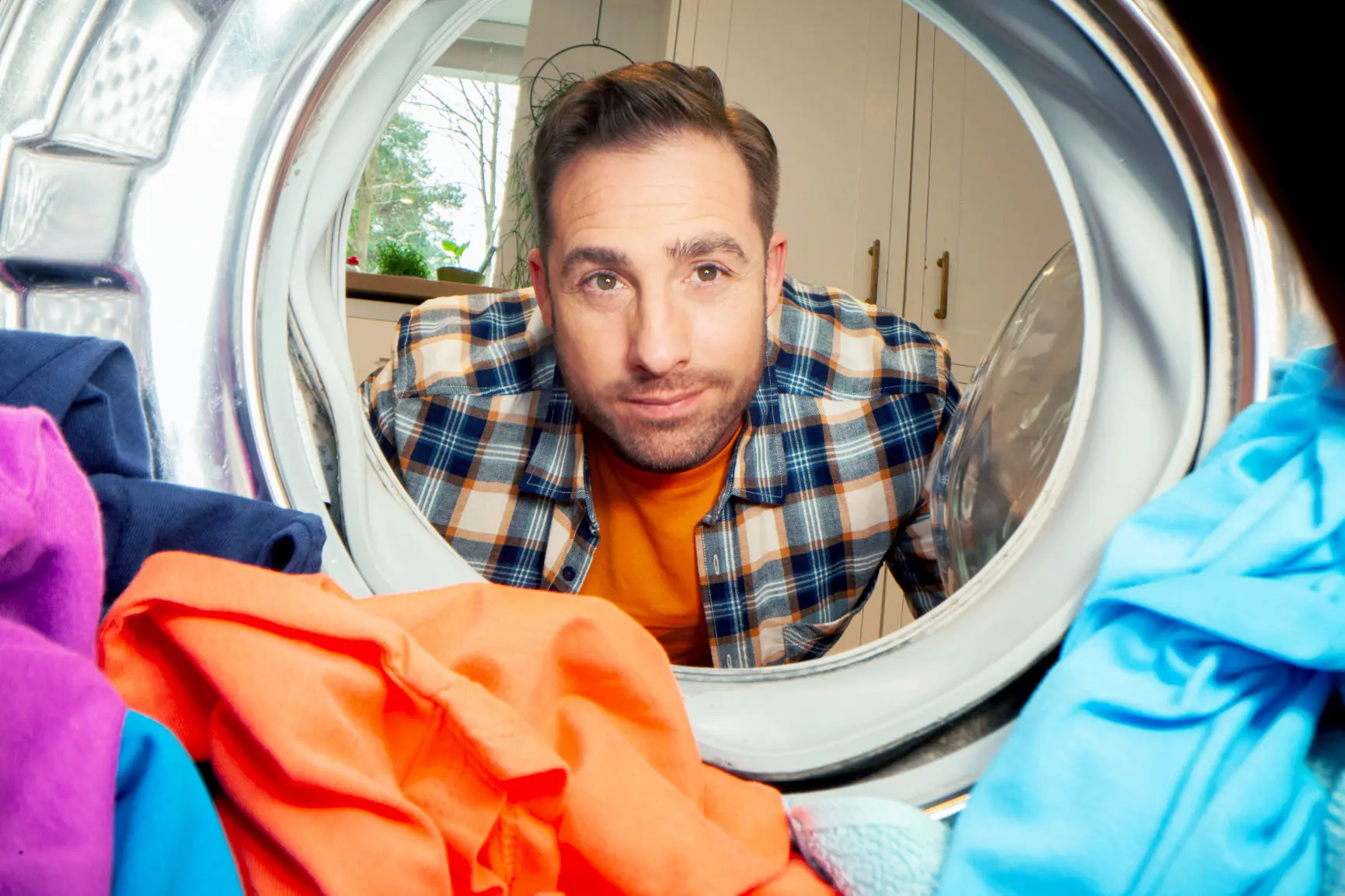 man looking into a washing machine full of clothes