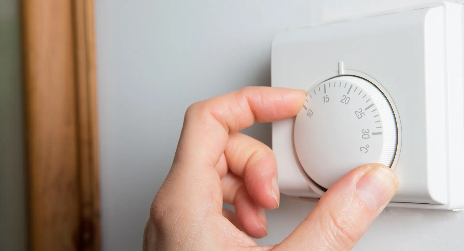 A person adjusting a thermostat