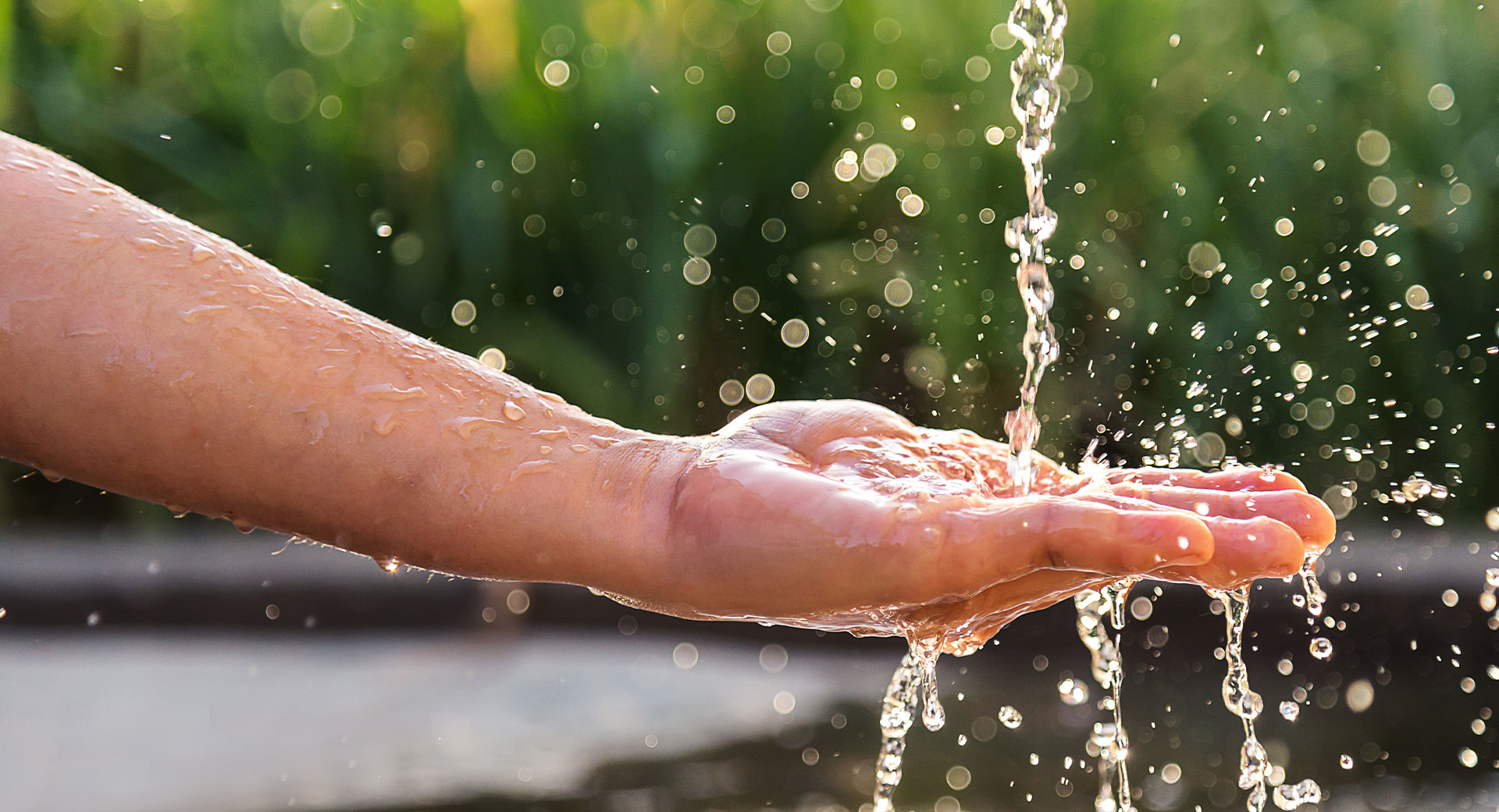 A close-up of water splashing into the palm of a person's hand