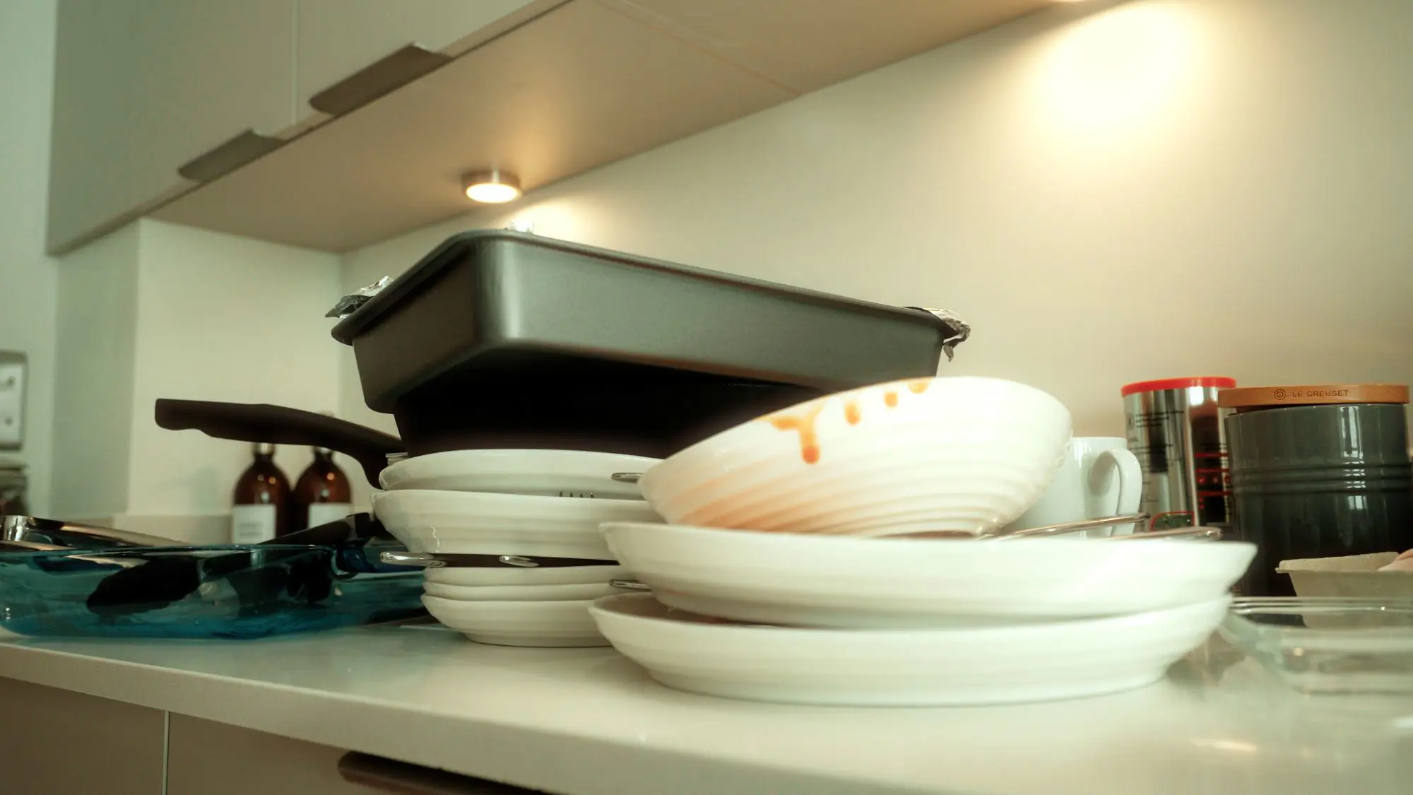 Pile of dirty greasy plates next to kitchen sink