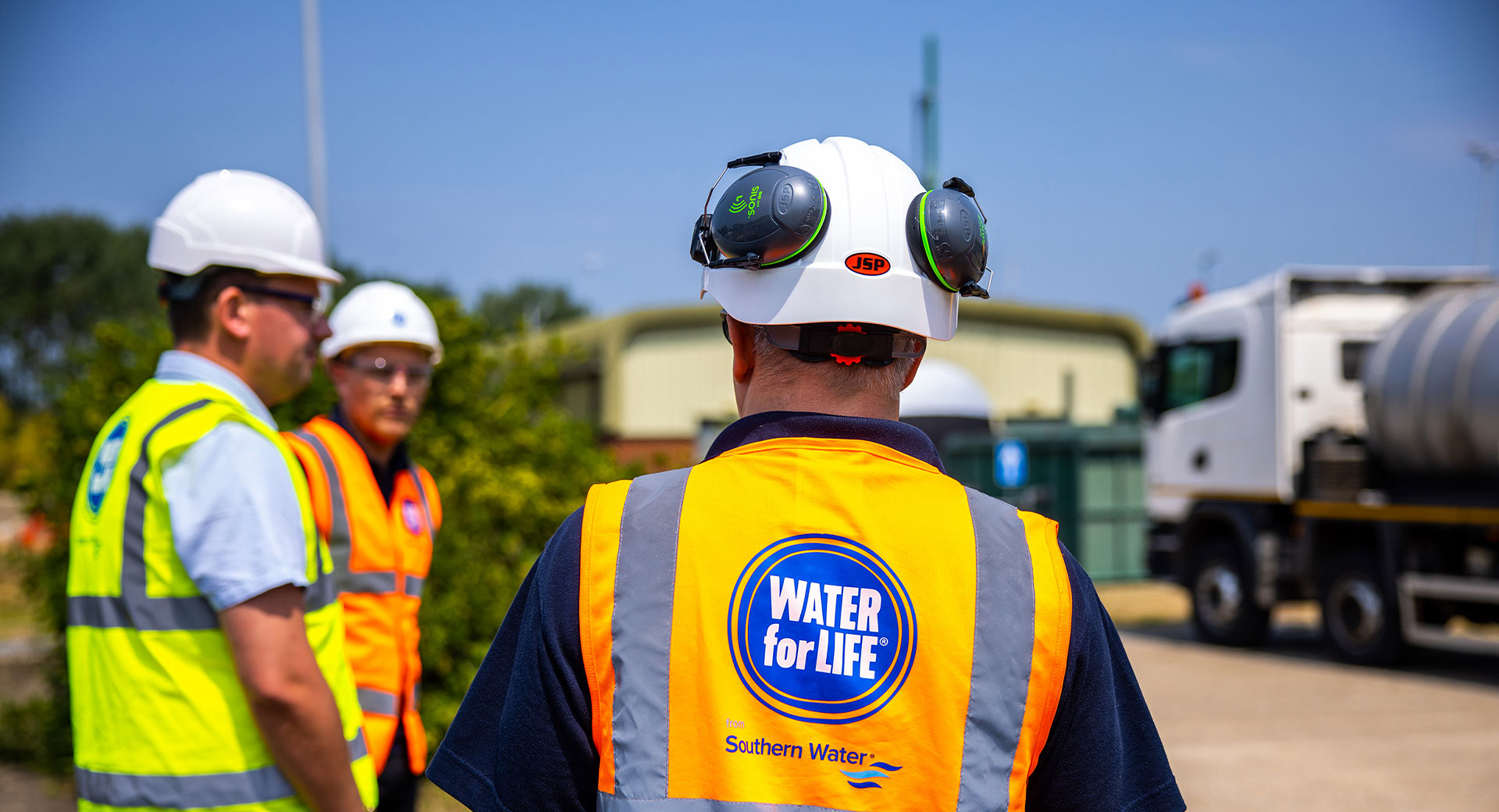 Three Southern Water employees look at a wastewater tanker