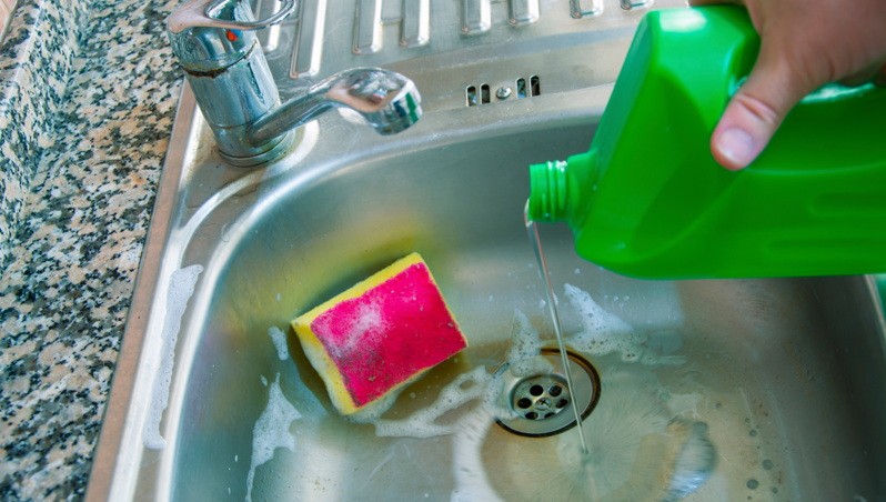 A person pouring bleach in a sink