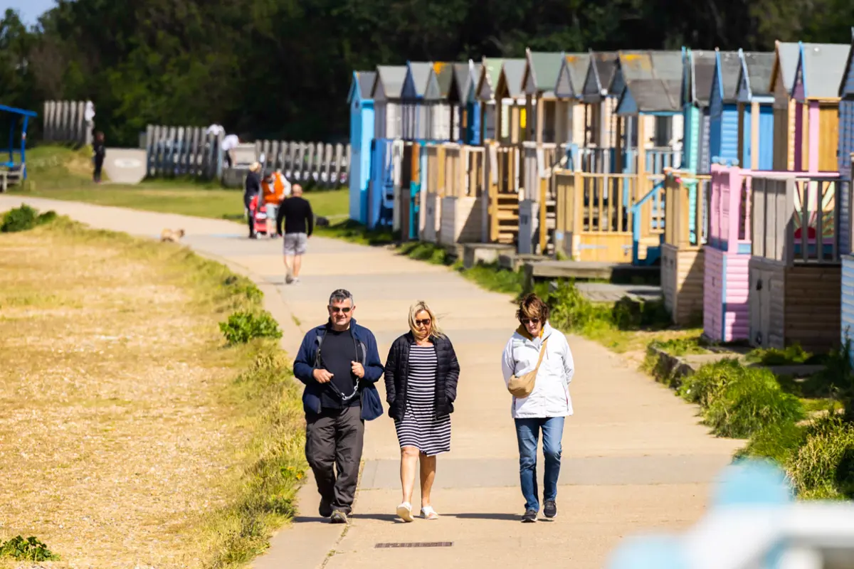 A close up shot of beach huts lining a promenade with people walking