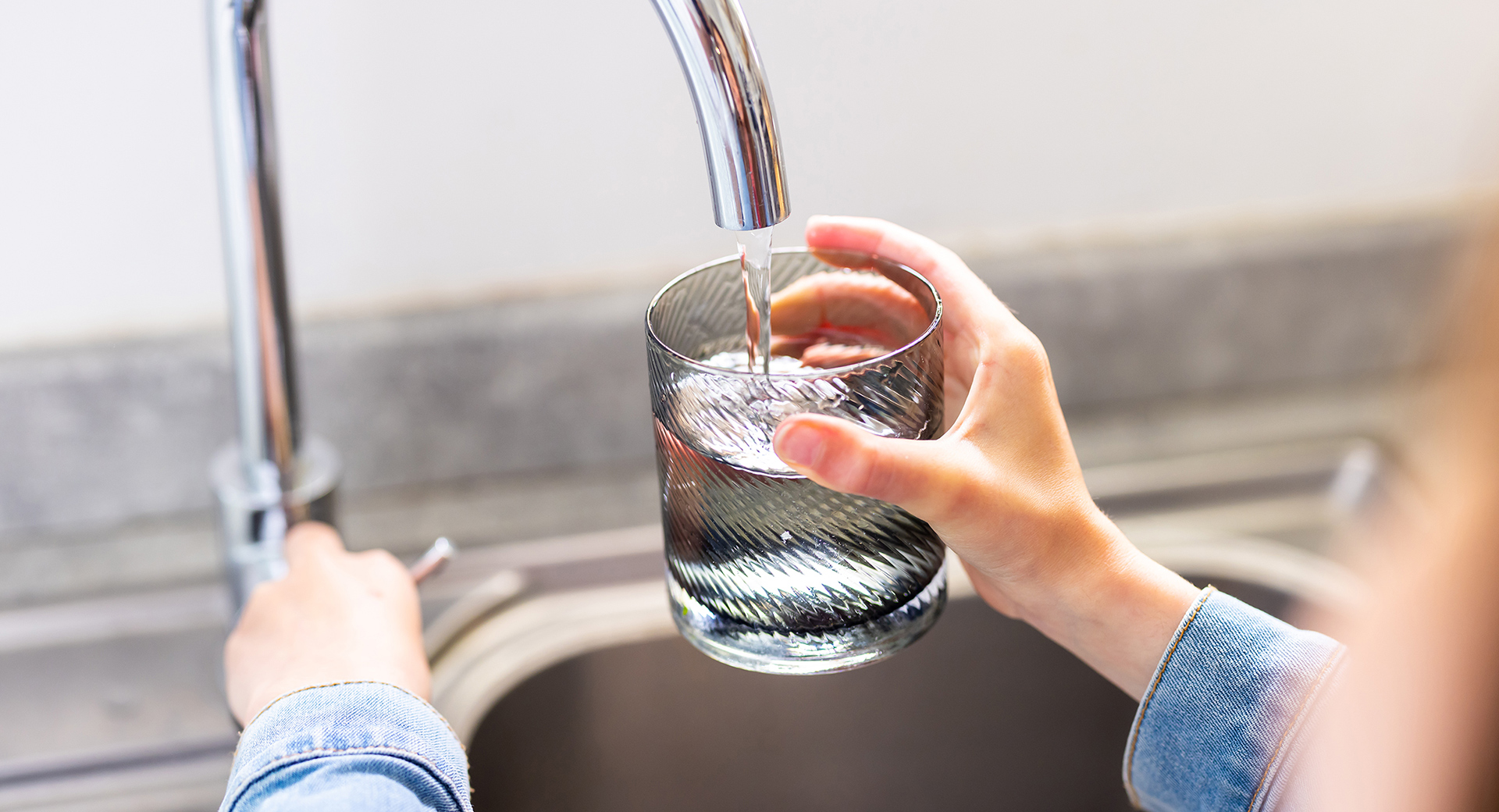 A close-up of a person filling a glass of water from a tap