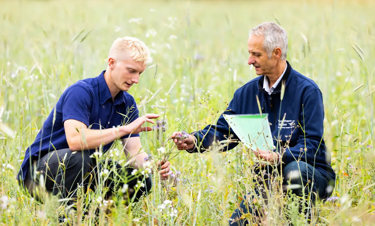 A photo of one person teaching the other in a field