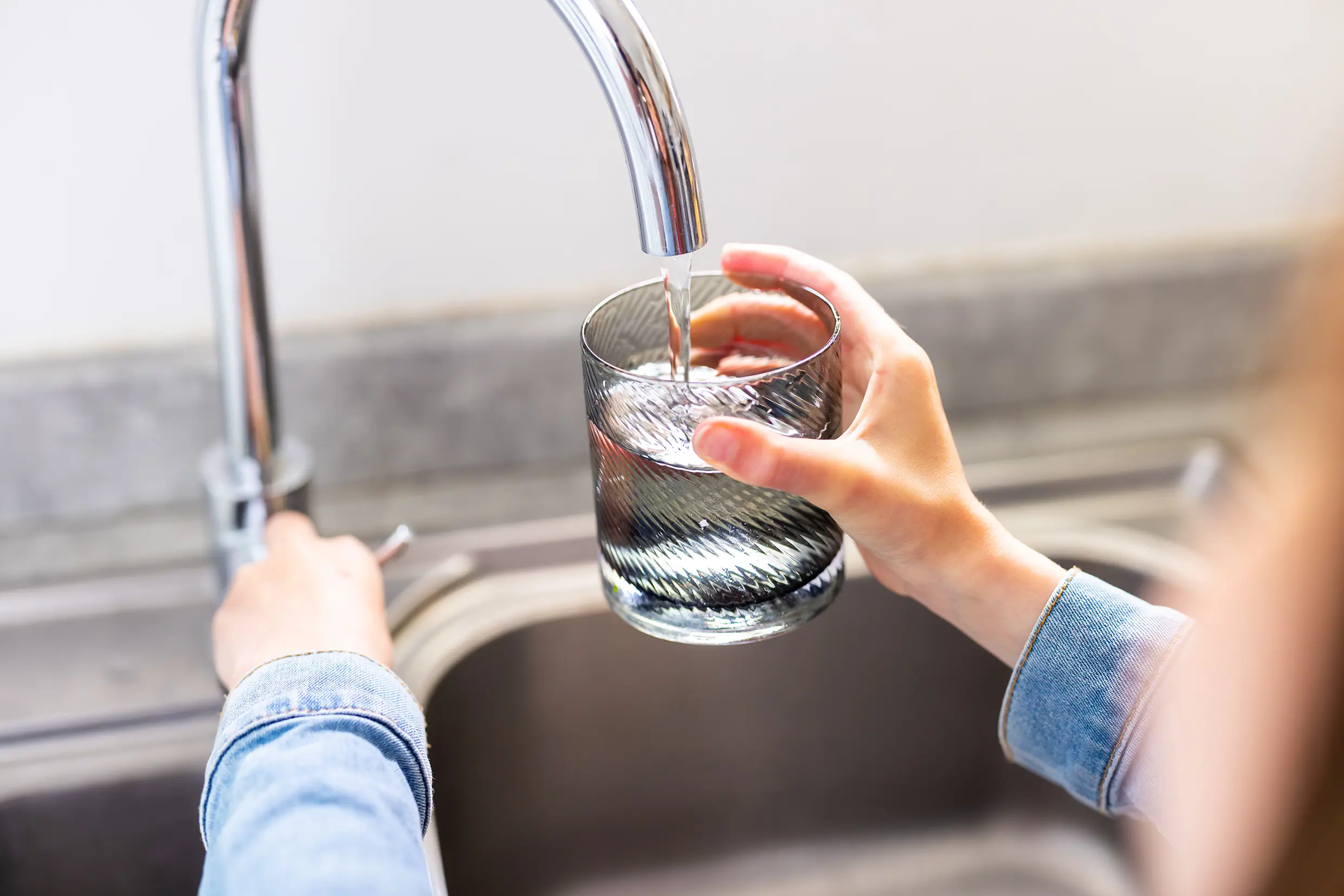 A close-up of a person filling a glass of water from a tap