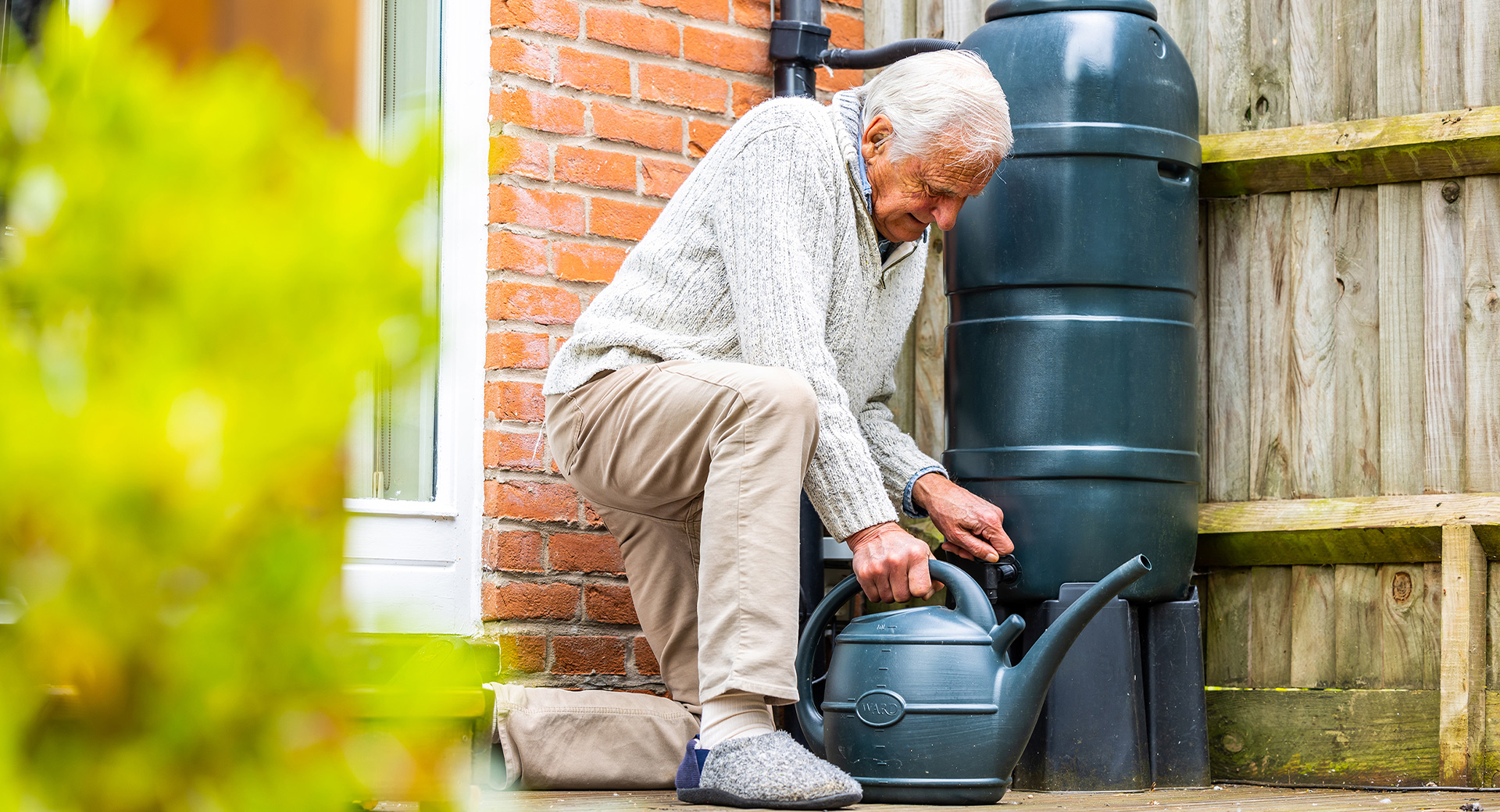 Elderly customer filling watering can
                        
