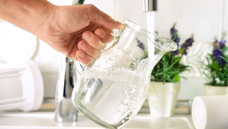 A glass jug being filled with tap water