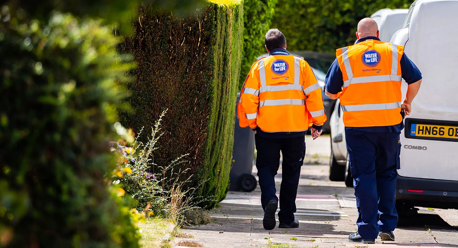 Two Southern Water engineers walk down a residential street on a sunny day